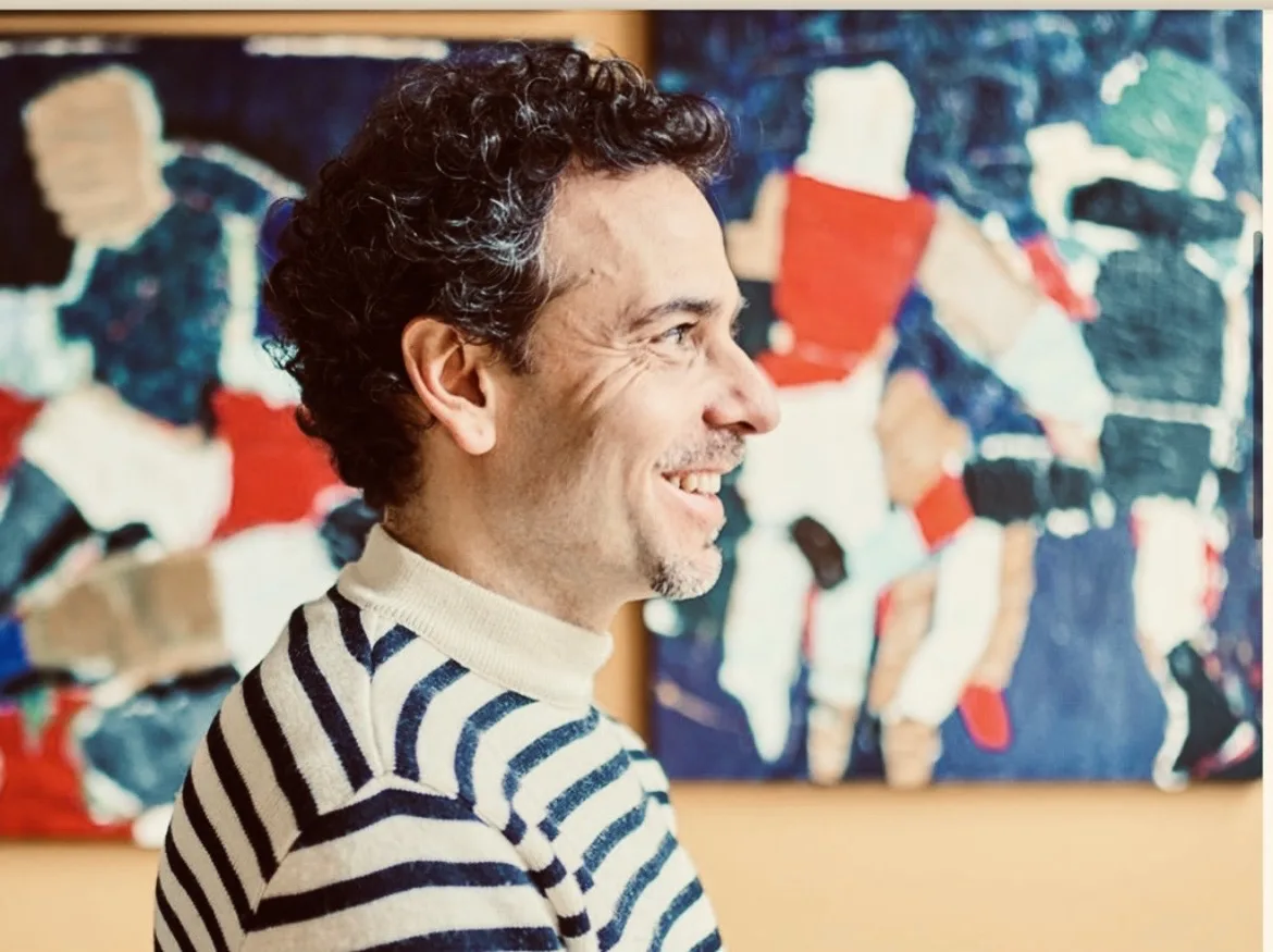 Tibor Lukács met zijn schilderijen op de achtergrond